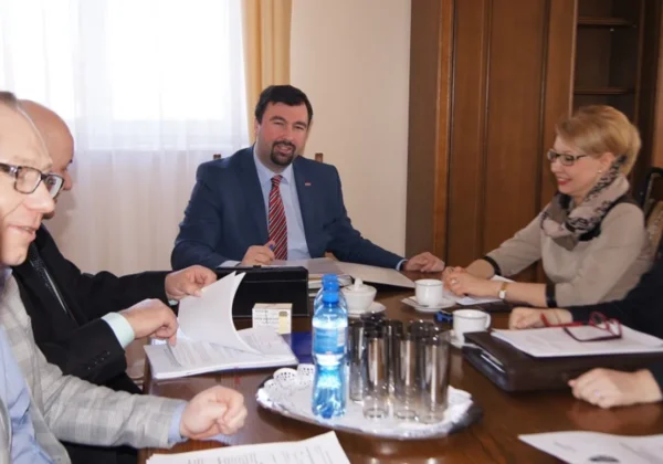Grupa urzędników Zarządu Powiatu w Płocku siedzi przy stole podczas formalnego spotkania i omawia dokumenty.