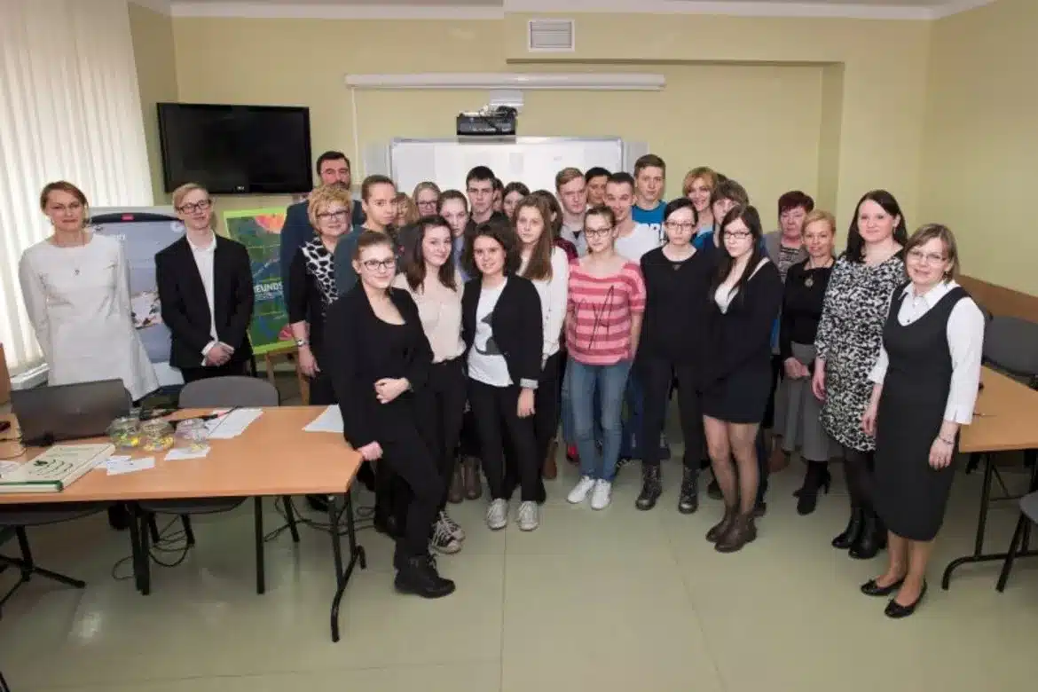 Uczestnicy V edycji Powiatowego Konkursu Wiedzy o Francji, Niemczech, Rosji i Wielkiej Brytanii stoją w grupie w sali, otoczeni przez nauczycieli i przygotowania do konkursu.