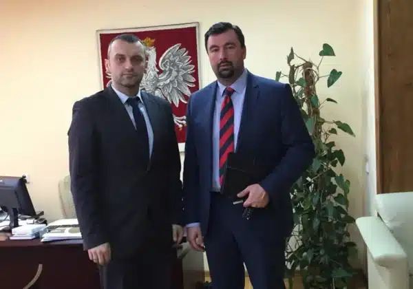 Starosta Płocki i jego rozmówca pozują do zdjęcia w biurze, w tle widoczna jest herbowa flaga i roślina doniczkowa.