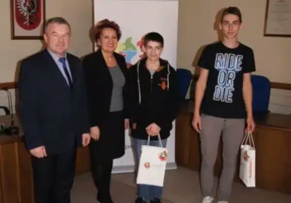 Na zdjęciu widoczni są uczestnicy lekcji wychowania obywatelskiego w Starostwie, stojący obok przedstawicieli urzędów, trzymający torby z upominkami.