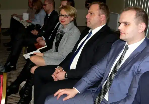 Na zdjęciu przedstawiono uczestników konferencji dotyczącej współpracy samorządów terytorialnych z operatorem systemu dystrybucji energii elektrycznej, siedzących w sali w formalnych strojach.