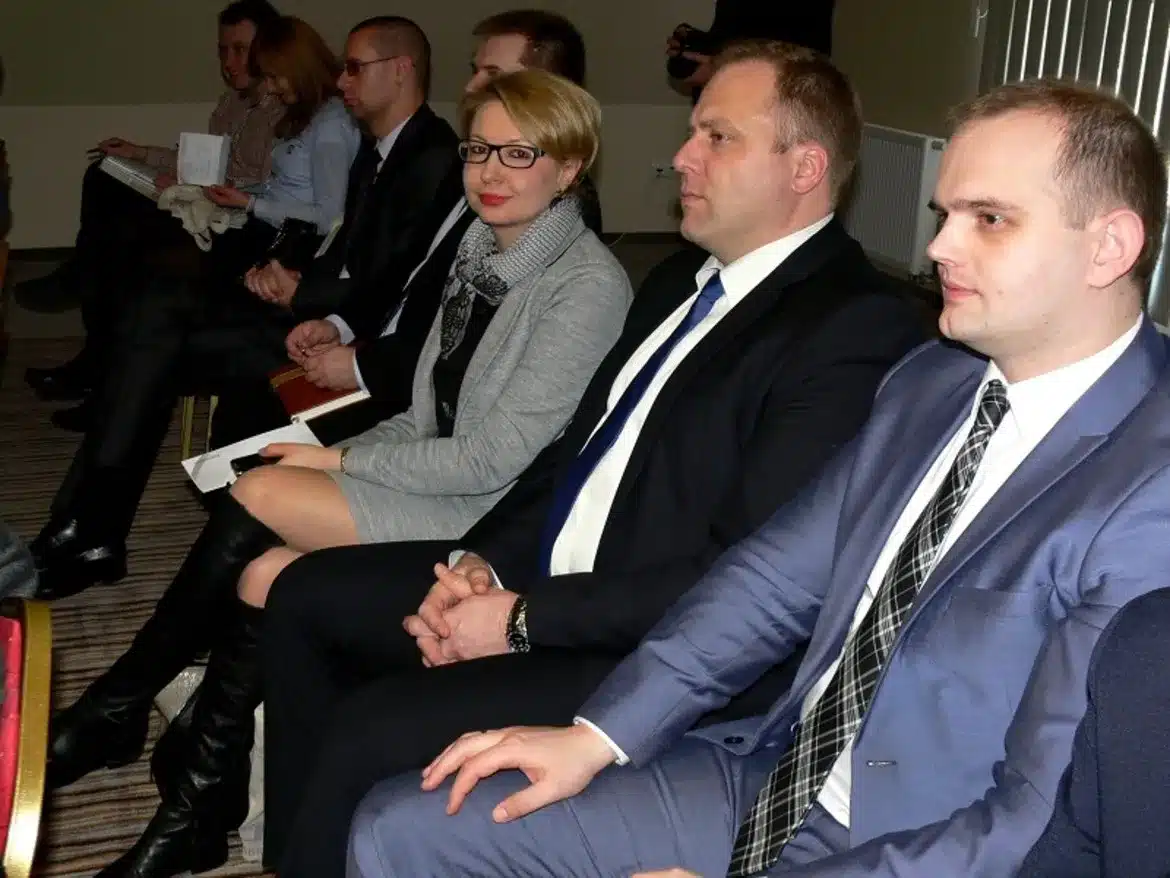 Na zdjęciu przedstawiono uczestników konferencji dotyczącej współpracy samorządów terytorialnych z operatorem systemu dystrybucji energii elektrycznej, siedzących w sali w formalnych strojach.