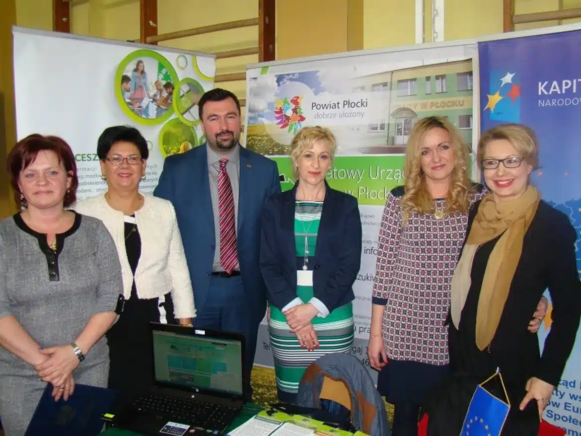 Na zdjęciu widać grupę osób stojących przy stoisku podczas VI Edycji Targów Edukacyjnych „Od edukacji do pracy” w Wyszogrodzie.