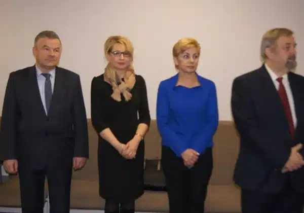 Wielkanocne spotkanie płockich funkcjonariuszy i pracowników policji, podczas którego uczestnicy stoją w równych odstępach w eleganckich strojach.