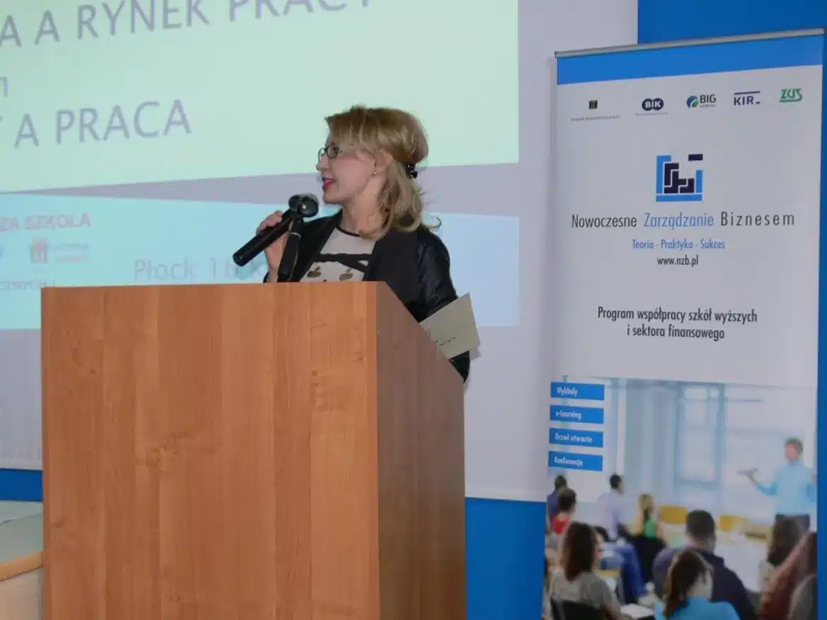 Na zdjęciu znajduje się prelegentka przemawiająca podczas V Międzynarodowej Konferencji Studenckich Kół Naukowych pt. „Student a praca”, z logo różnych instytucji na tle.