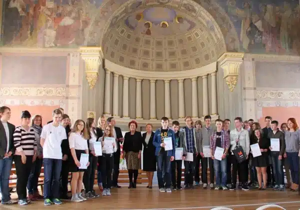 Grupa uczniów z certyfikatami stoi na scenie w eleganckiej sali podczas wydarzenia Malachoviacus Informaticus.