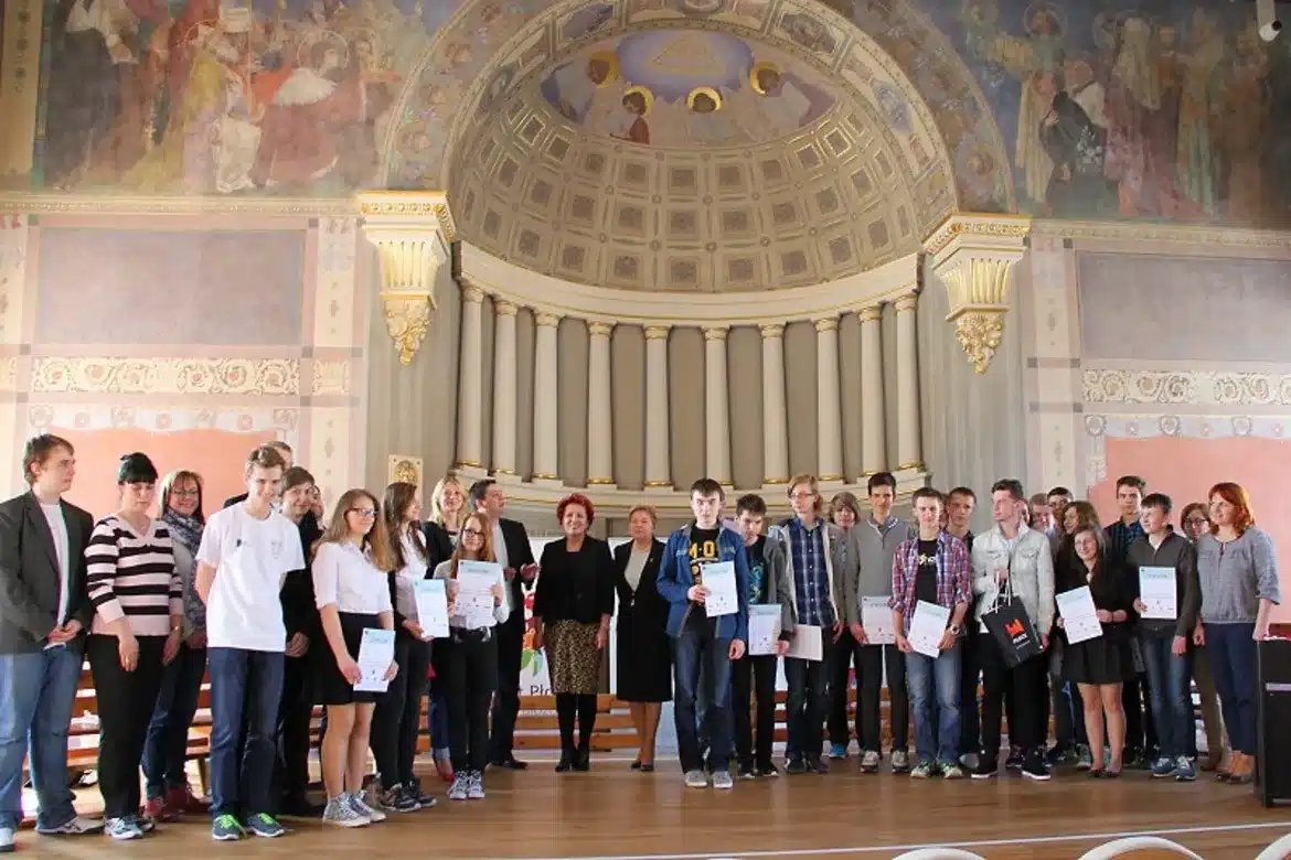 Grupa uczniów z certyfikatami stoi na scenie w eleganckiej sali podczas wydarzenia Malachoviacus Informaticus.