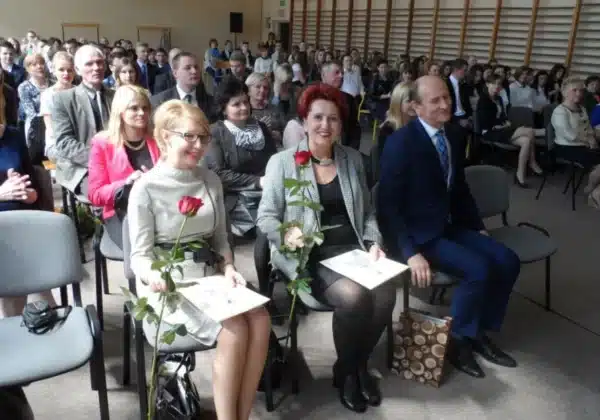 Wręczenie świadectw w Zespole Szkół w Gąbinie, gdzie obecni goście z uśmiechami i kwiatami w rękach celebrują ten wyjątkowy moment.