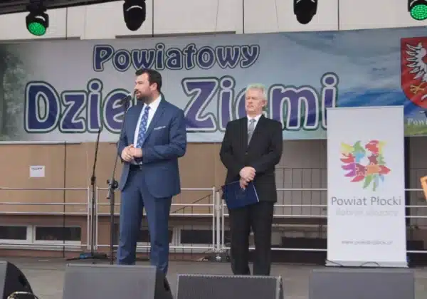 Na zdjęciu przedstawiono dwóch mężczyzn stojących na scenie podczas XVI Powiatowego Dnia Ziemi w Słubicach, z banerem w tle.