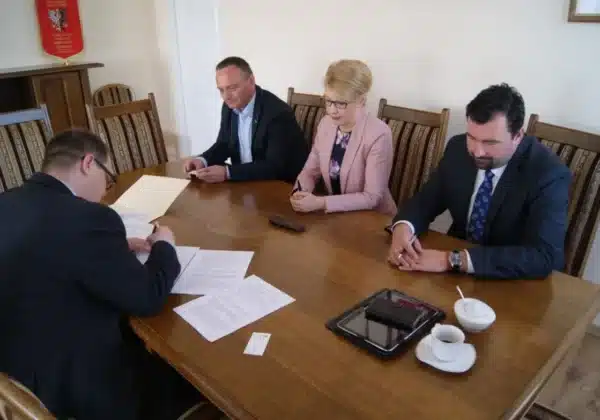 Na zdjęciu przedstawiono moment podpisania umowy dotyczącej przebudowy drogi powiatowej nr 2944W Radzanowo – Bodzanów w towarzystwie kilku osób siedzących przy stole.