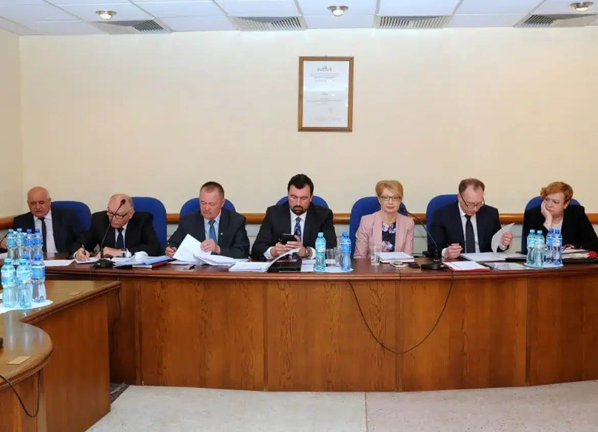 Uczestnicy V Sesji Rady Powiatu w Płocku zasiadają przy stole, omawiając dokumenty i przygotowując się do obrad.