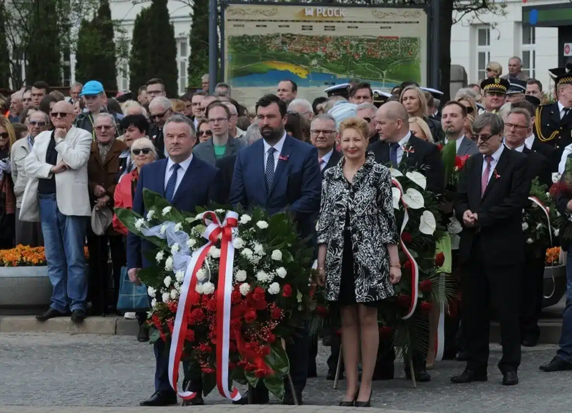 Obrazek przedstawia uczestników uroczystości z okazji 224. rocznicy uchwalenia Konstytucji 3 Maja, którzy składają kwiaty na tle zgromadzonej publiczności w Płocku.