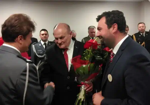 Na zdjęciu przedstawiono emocjonalną chwilę pożegnania Komendanta Miejskiego Policji w Płocku, który odchodzi na emeryturę, w otoczeniu współpracowników i kwiatów.