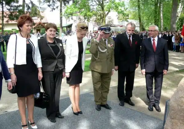 Grupa osób, w tym żołnierz w mundurze oraz przedstawiciele lokalnych władz, uczestniczy w obchodach Narodowego Dnia Zwycięstwa w Gminie Mała Wieś.
