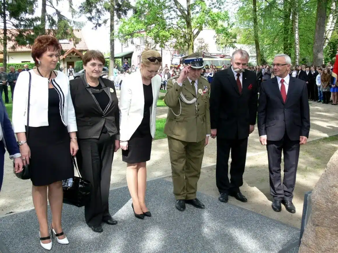Grupa osób, w tym żołnierz w mundurze oraz przedstawiciele lokalnych władz, uczestniczy w obchodach Narodowego Dnia Zwycięstwa w Gminie Mała Wieś.