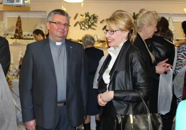 Na zdjęciu widać uśmiechniętych uczestników spotkania opłatkowego w Domu Pomocy Społecznej, rozmawiających w świątecznej atmosferze.