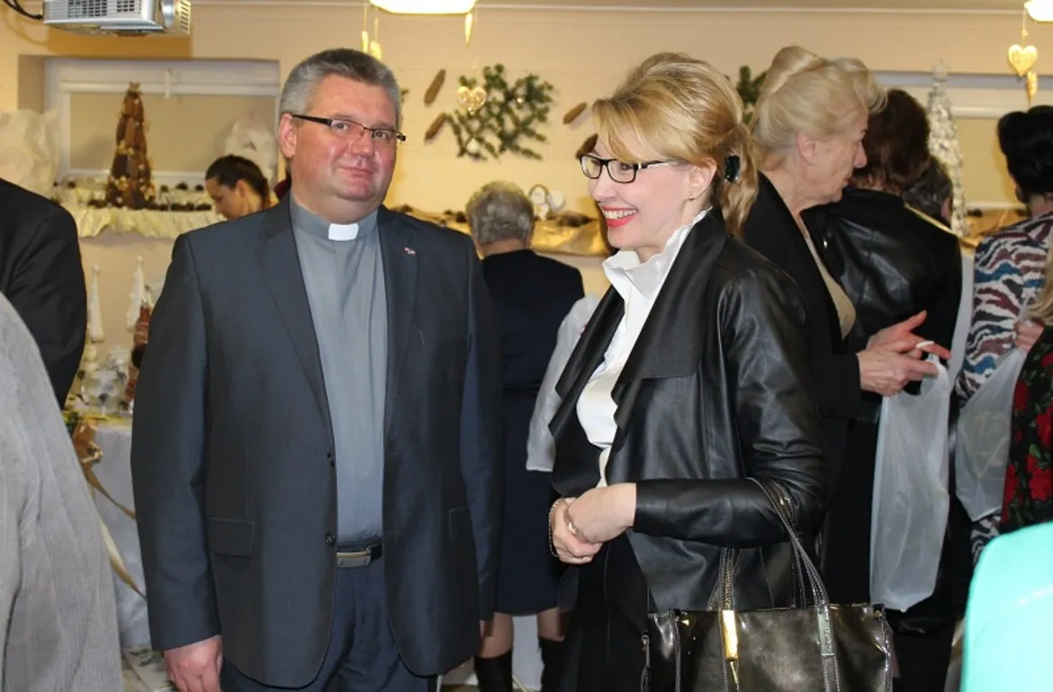 Na zdjęciu widać uśmiechniętych uczestników spotkania opłatkowego w Domu Pomocy Społecznej, rozmawiających w świątecznej atmosferze.