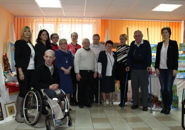 Grupa mieszkańców Domu Pomocy Społecznej w Koszelewie w towarzystwie pracowników Starostwa Powiatowego w Płocku na wspólnej fotografii w sali urzędowej.