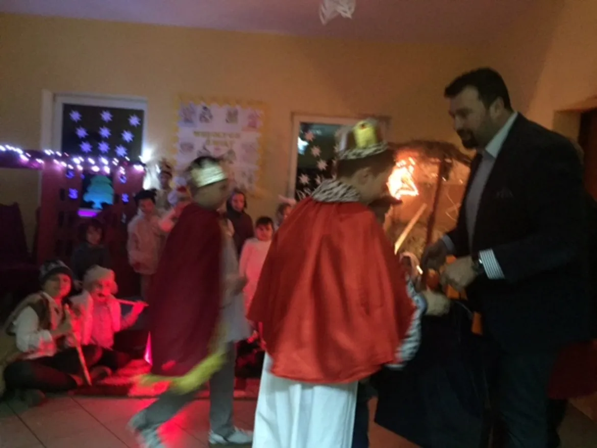 Zdjęcie przedstawia dzieci w kostiumach, biorące udział w świątecznym przedstawieniu, z dekoracjami w tle w Grodkowie.