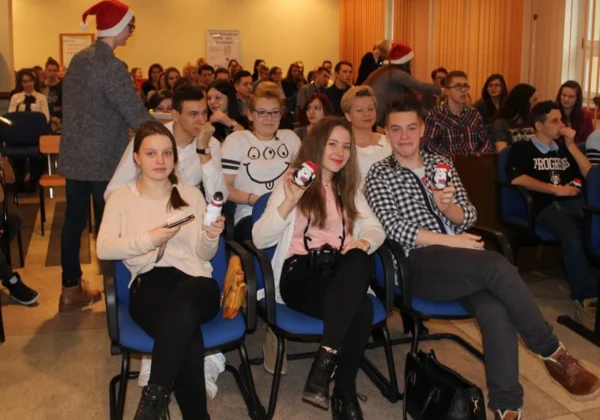 Na zdjęciu widać młodych ludzi siedzących na sali podczas gali wolontariatu „Wolontariat jest dla każdego”, trzymujących w rękach przedmioty z wizerunkiem Mikołaja.
