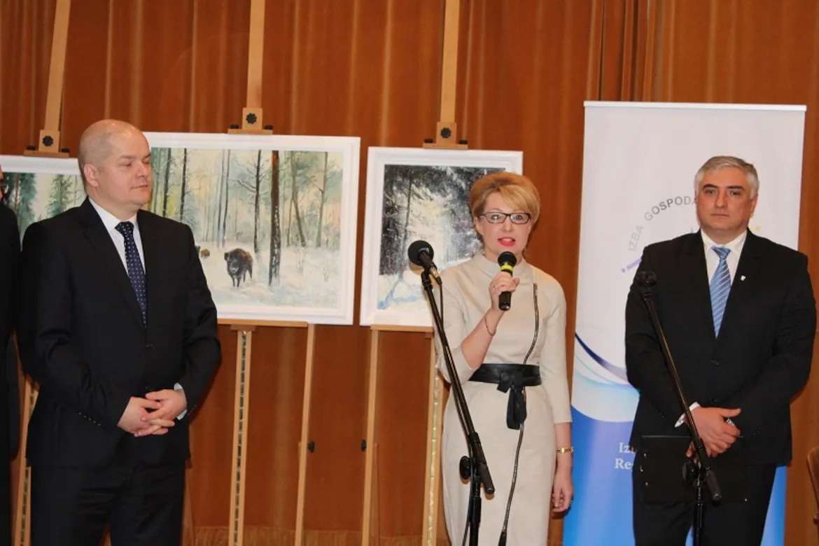 Uczestnicy spotkania wigilijnego IGRP, w tym mówca z mikrofonem, prezentują się na tle obrazów przedstawiających zimowy krajobraz.