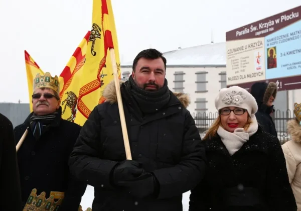 Na zdjęciu uczestnicy Orszaku Trzech Króli w Płocku, stojący w zimowej scenerii z flagami i korony na głowach.