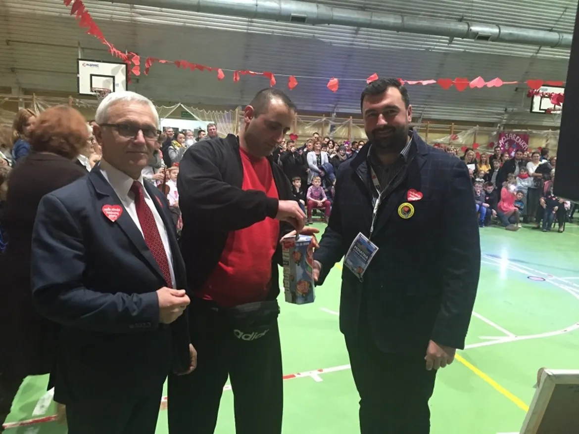 Na zdjęciu trzech mężczyzn uczestniczy w finale WOŚP, wręczając i odbierając datki w atmosferze wsparcia i charytatywnego zaangażowania.