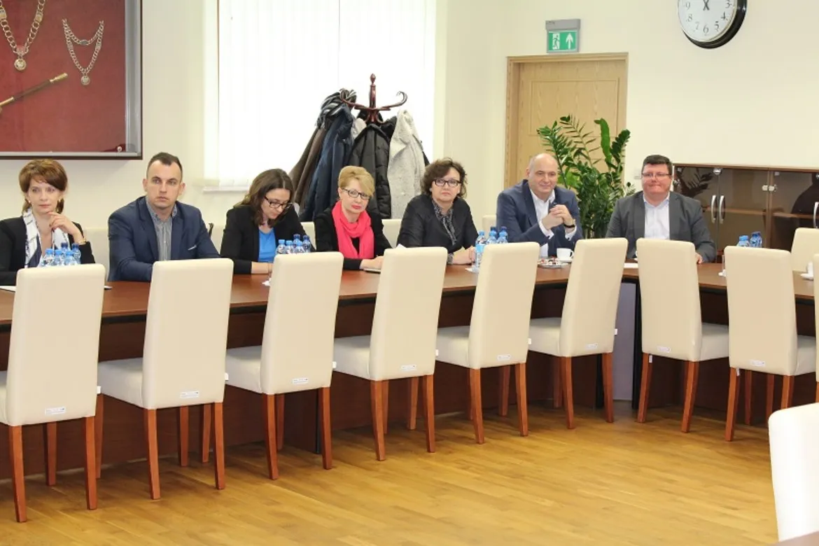 Na zdjęciu uczestnicy Konwentu PWSZ w Płocku siedzą przy długim stole w sali konferencyjnej, dyskutując w gronie przedstawicieli różnych instytucji.