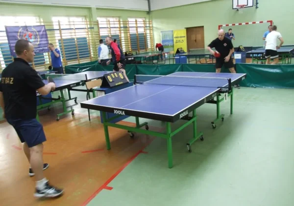 Otwarte zawody w tenisie stołowym, w trakcie których zawodnicy rywalizują przy stołach w sali sportowej.