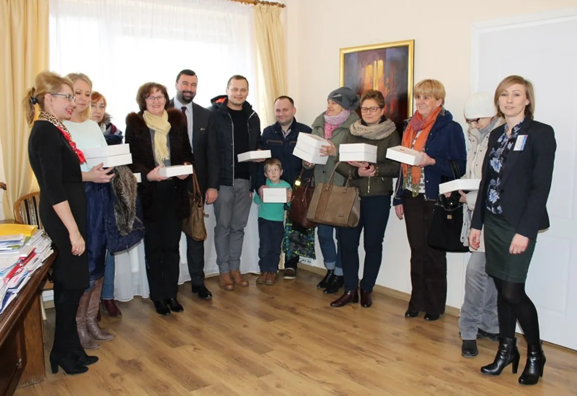 Uczestnicy tłustoczwartkowego konkursu pozują w grupie, trzymając pudełka z nagrodami.