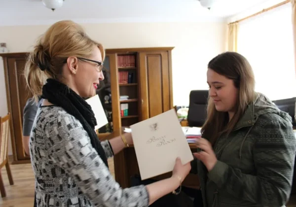 Na zdjęciu dwie kobiety uśmiechają się podczas wręczenia nagrody w Świątecznym Konkursie Mikołaja.