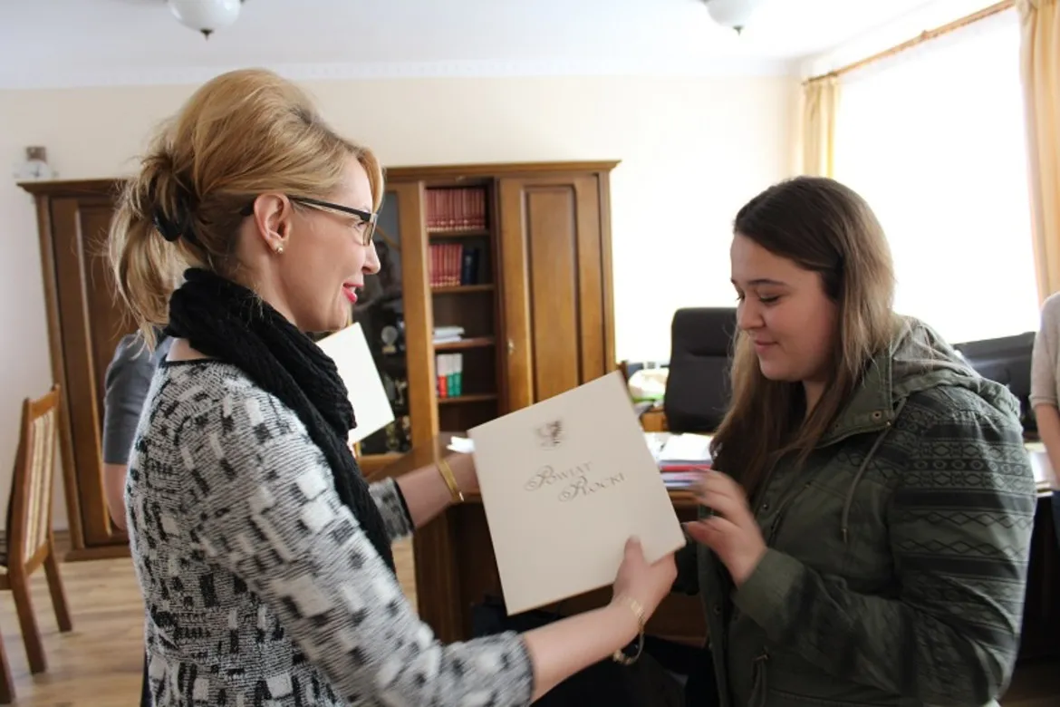 Na zdjęciu dwie kobiety uśmiechają się podczas wręczenia nagrody w Świątecznym Konkursie Mikołaja.