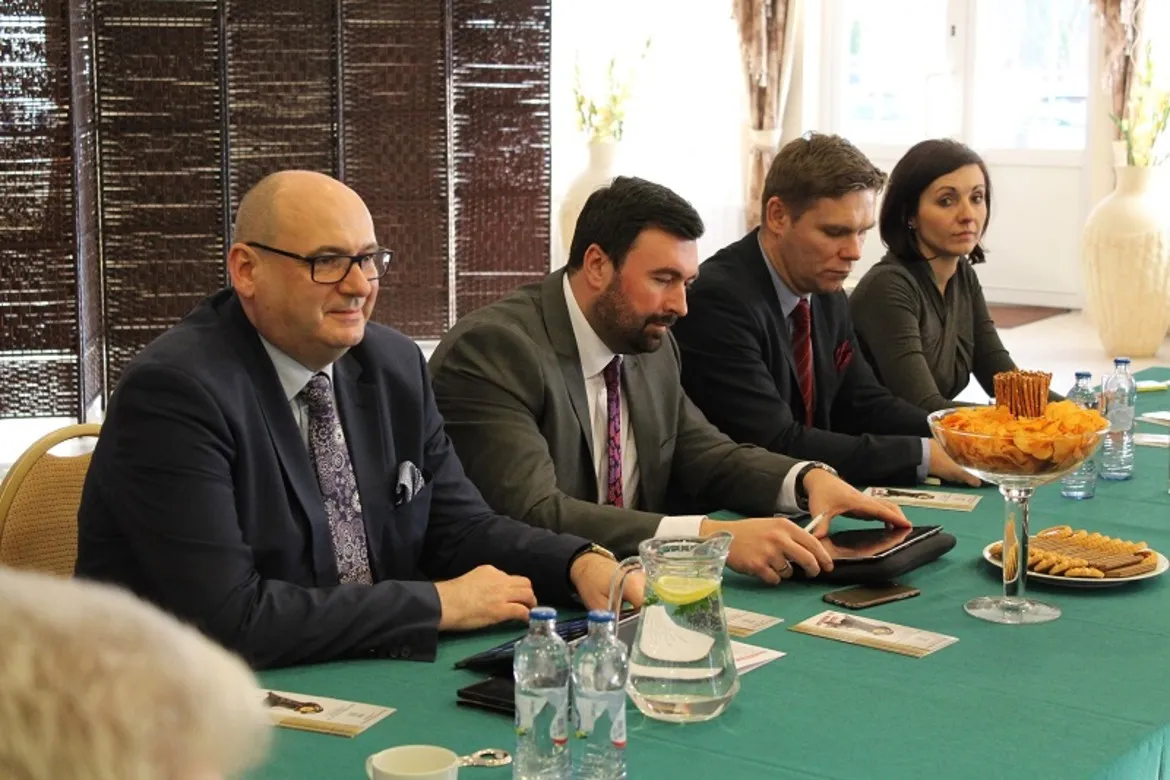 Uczestnicy konwentu samorządowego w powiecie płockim siedzą przy stole w trakcie spotkania, otoczeni przekąskami i wodą.