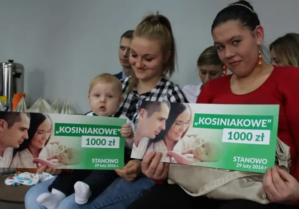 Na zdjęciu widać grupę rodziców z dziećmi trzymających plakaty informujące o programie „kosiniakowe”, które zostały wręczone w powiecie płockim.