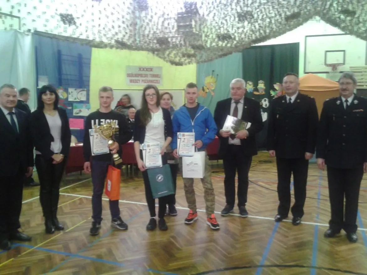 Zdjęcie przedstawia laureatów Ogólnopolskiego Konkursu Wiedzy Pożarniczej w powiecie płockim, którzy stoją z nagrodami i dyplomami w towarzystwie organizatorów wydarzenia.