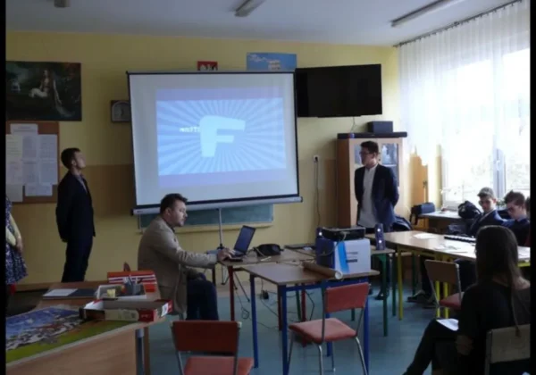 Uczniowie i nauczyciele uczestniczą w prezentacji dotyczącej bezpieczeństwa w internecie w klasie.