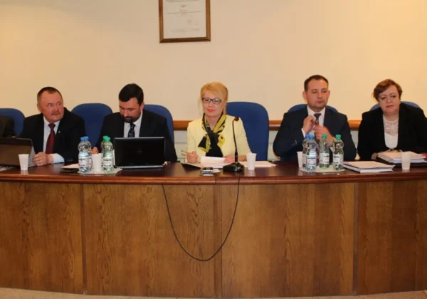 Grupa samorządowców siedzi przy długim stole na sali obrad podczas XV sesji Rady Powiatu w Płocku (kadencja 2014–2018), z laptopami, mikrofonem i dokumentami przed sobą.