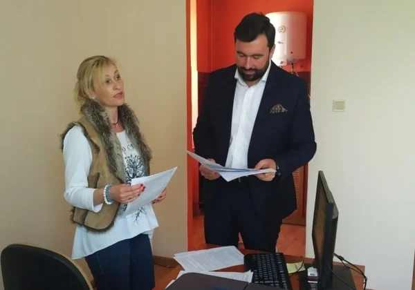 Kobieta i mężczyzna w biurze Punktu Rejestracji Oświadczeń w Wyszogrodzie przeglądają dokumenty przy biurku z komputerem.