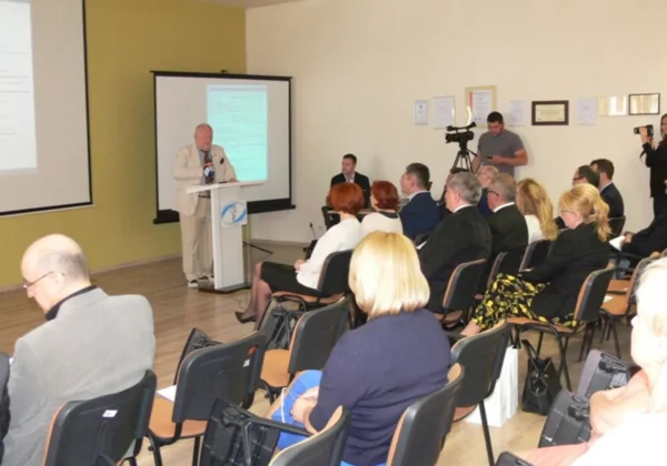 Mówca w jasnym garniturze przemawia z podium podczas konferencji „Medycyna ratunkowa 2016 – perspektywy i kierunki rozwoju”, przed salą z uczestnikami i nagrywającą ekipą.