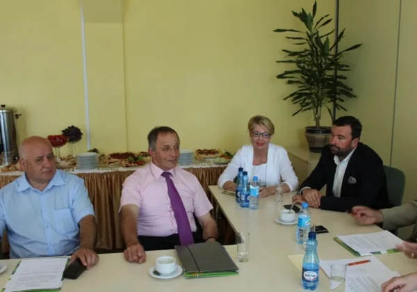 Grupa osób siedzi przy stole w sali konferencyjnej podczas zakończenia kadencji Powiatowej Rady Zatrudnienia; na stole są dokumenty, filiżanki i butelki wody, a w tle widoczny jest bufet z przekąskami.