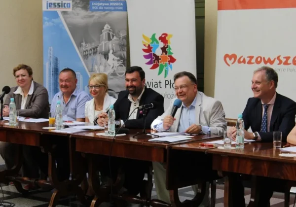 Grupa samorządowców siedzi przy stole podczas konferencji w powiecie płockim, omawiając przeznaczenie 2,9 mln zł na bezpieczeństwo i turystykę, przy bannerach Mazowsza i Powiatu Płockiego w tle.