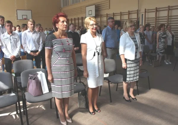 Grupa osób stoi na sali gimnastycznej podczas uroczystości wręczenia świadectw Zasadniczej Szkoły Zawodowej w Zespole Szkół w Gąbinie.
