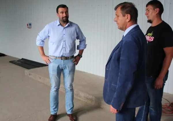 Trzech mężczyzn stoi i rozmawia w nieukończonej hali szkolnej podczas przygotowań do nowego roku szkolnego w Zespole Szkół im. Jana Śniadeckiego w Wyszogrodzie.