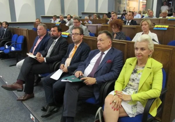 Grupa samorządowców w garniturach siedzi w pierwszym rzędzie sali sesyjnej podczas spotkania „Razem dla rozwoju dróg północnego Mazowsza”.