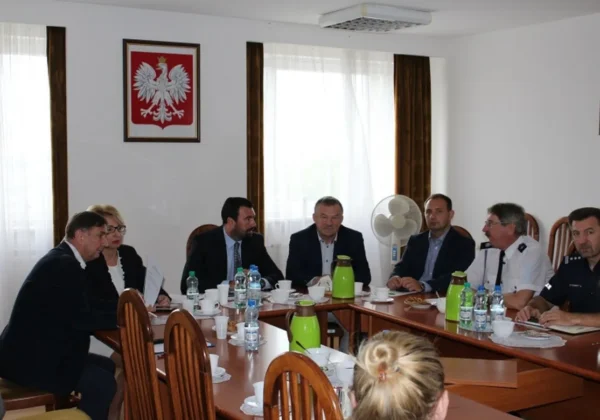 Członkowie Powiatowego Zespołu Zarządzania Kryzysowego siedzą przy stole konferencyjnym w sali urzędu i omawiają kwestie ASF.