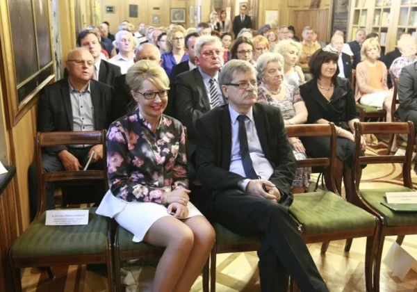 Na zdjęciu w pierwszym rzędzie sali konferencyjnej siedzi para: kobieta w kwiecistej marynarce i biała spódnica oraz mężczyzna w garniturze z niebieskim krawatem, podczas debaty o emeryturach w TNP.