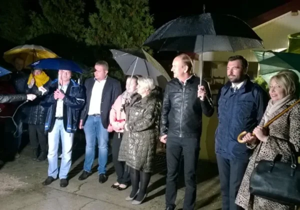 Grupa ludzi z parasolami stoi na zewnątrz wieczorem w Nowym Grabiu podczas wydarzenia z zapalaniem lamp solarnych.