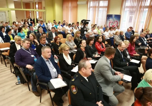 Uczestnicy międzynarodowej konferencji szkoleniowo-naukowej „Człowiek w obliczu zmiany” siedzą w sali konferencyjnej, słuchając prelekcji, przy czym w tle widoczna jest kamera na statywie.