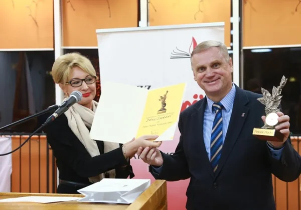 Kobieta wręcza mężczyźnie dyplom i statuetkę podczas uroczystości Dnia Edukacji Narodowej płockiej Solidarności.