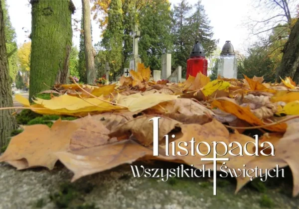 Jesienny cmentarz: na nagrobku leżą żółto-brązowe liście, w tle widoczne zapalone znicze i krzyże.